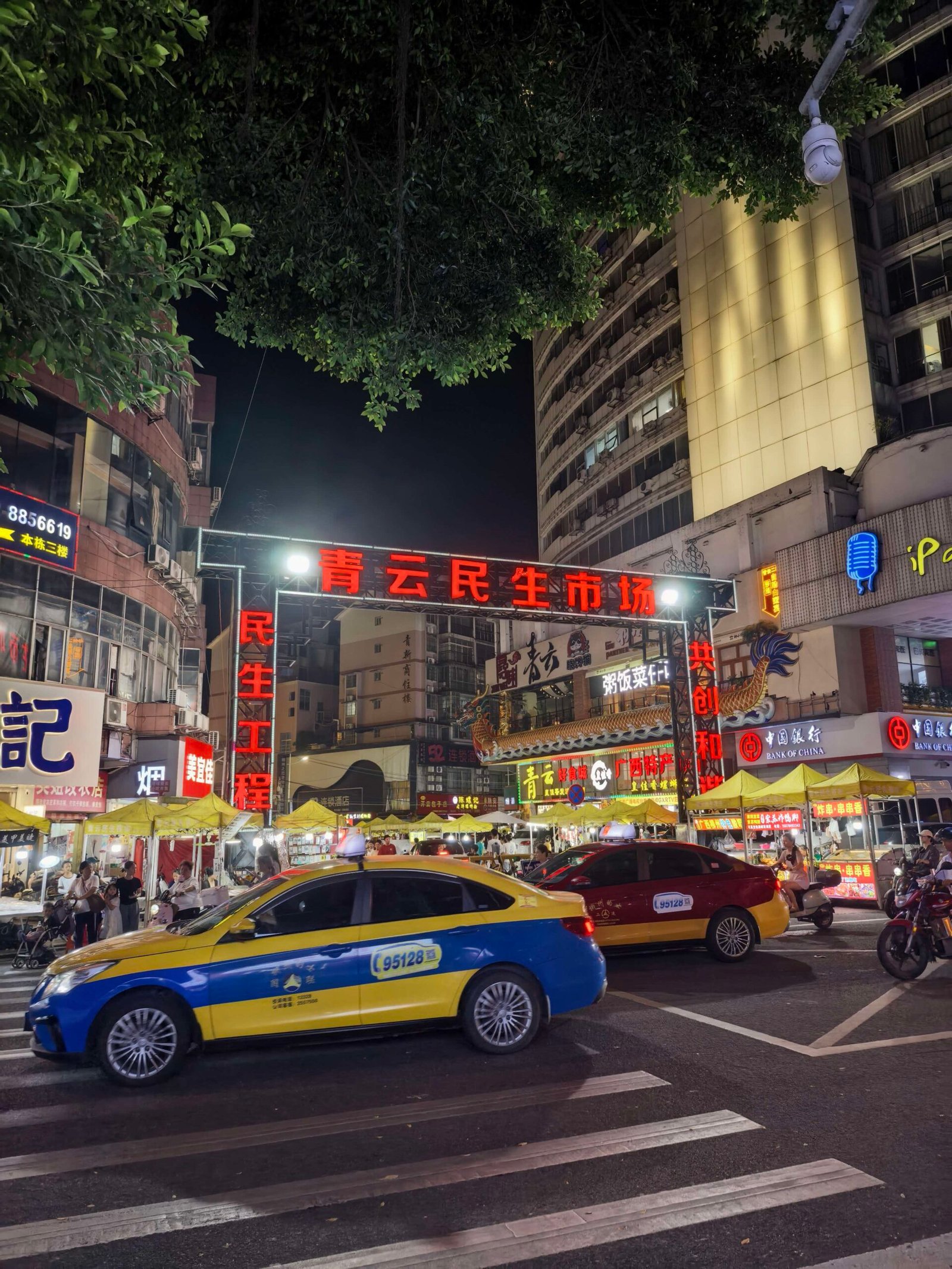 Night view of Qingyun Minsheng Market food street in Liuzhou with neon signage and food stalls