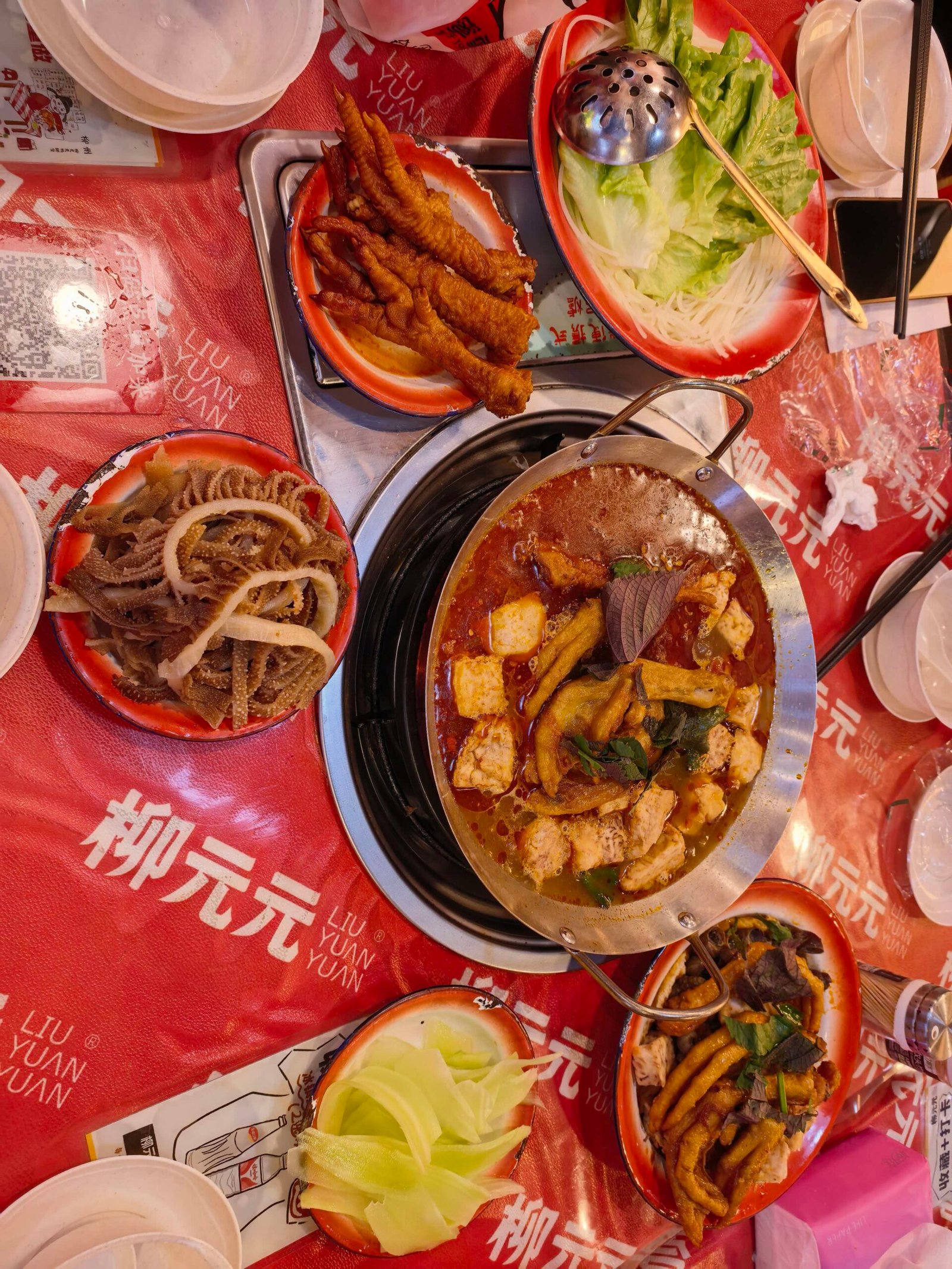 Table spread at Liu Yuan Yuan restaurant in Liuzhou with a central hot pot and side dishes of fried tofu skin and pickled vegetables