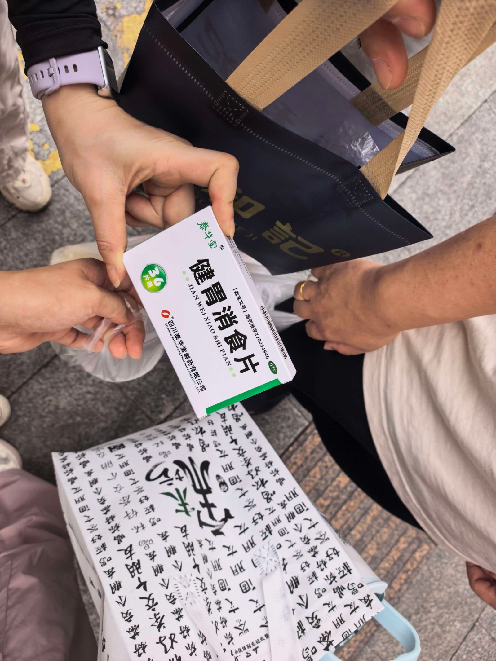 Hand holding a box of digestive tablets on a Liuzhou street, a lighthearted moment during a food tour