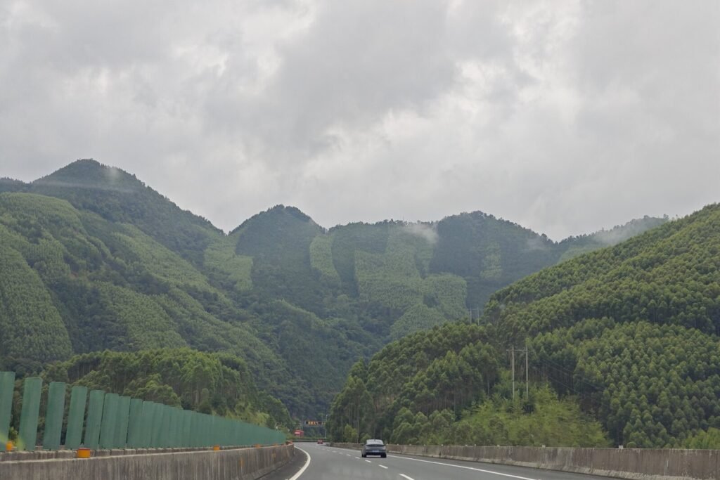 Green karst hills rising on both sides of the expressway approaching Liuzhou, Guangxi