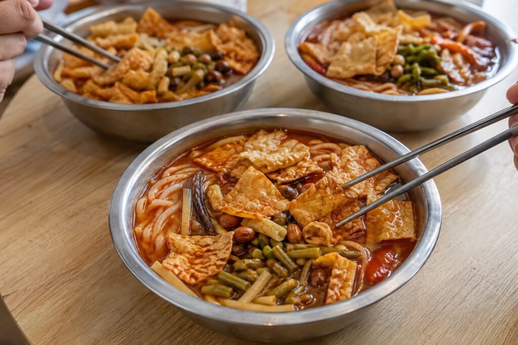 Three bowls of luosifen being shared around a wooden table