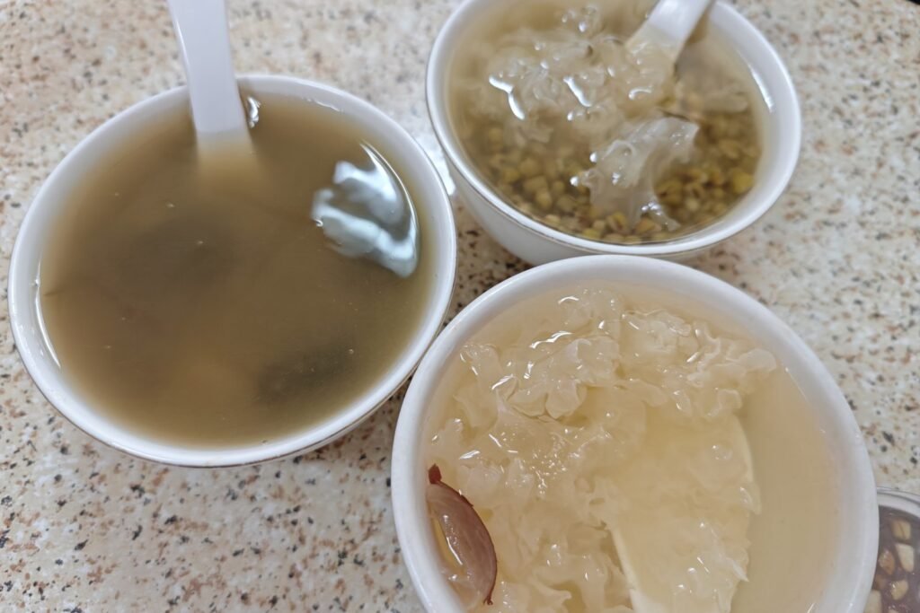 Three porcelain bowls of Cantonese sweet soup on a stone table in Zhanjiang